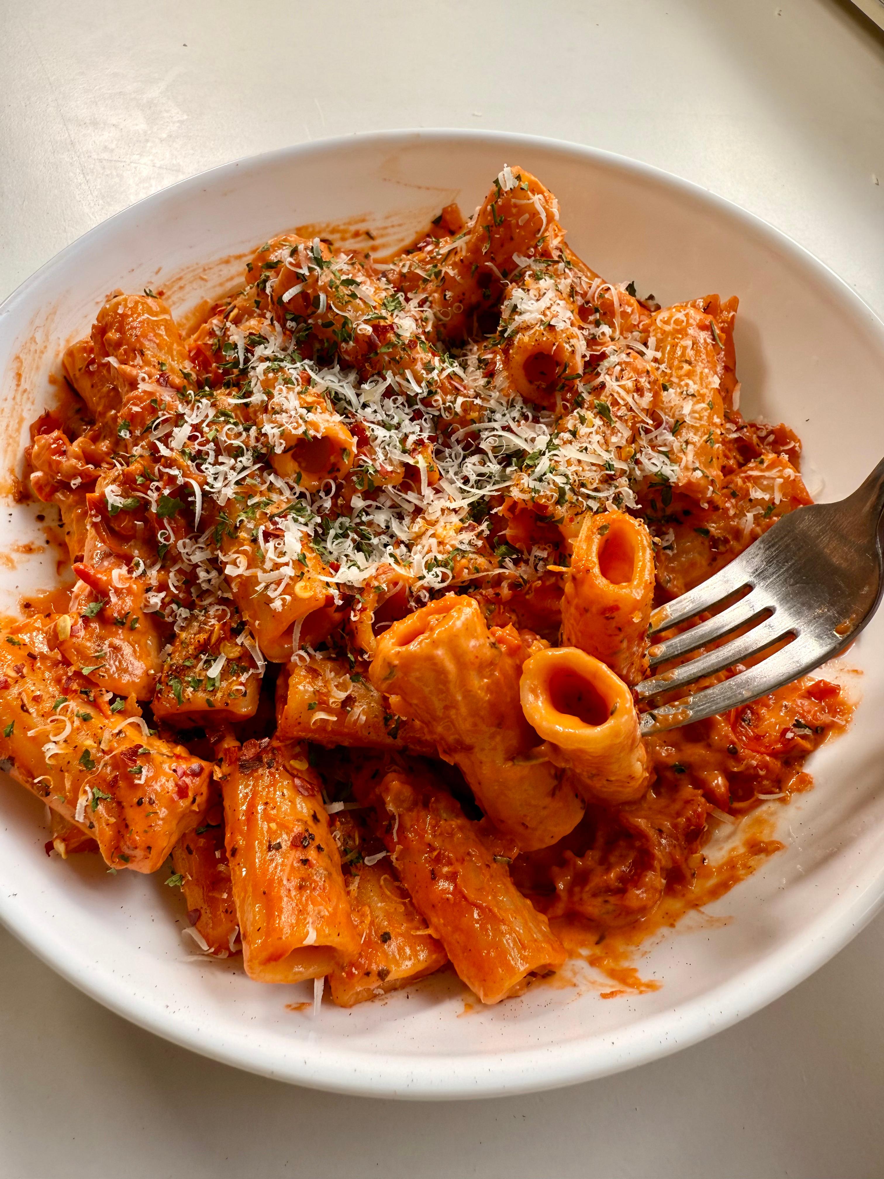 Creamy cherry tomato pasta plated with a fork resting on the side, showing the texture of the sauce and pasta.