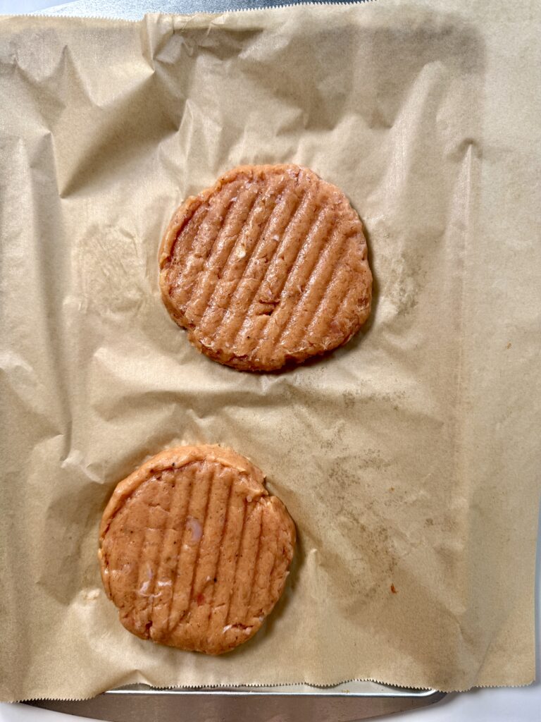Formed raw chicken patties made from ground chicken breast and thigh, ready to freeze